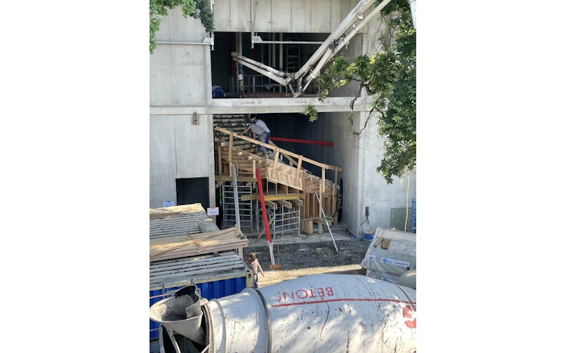 De houten bekisting van de trap wordt met een betonpomp trede voor trede gevuld (foto: W Architectures)